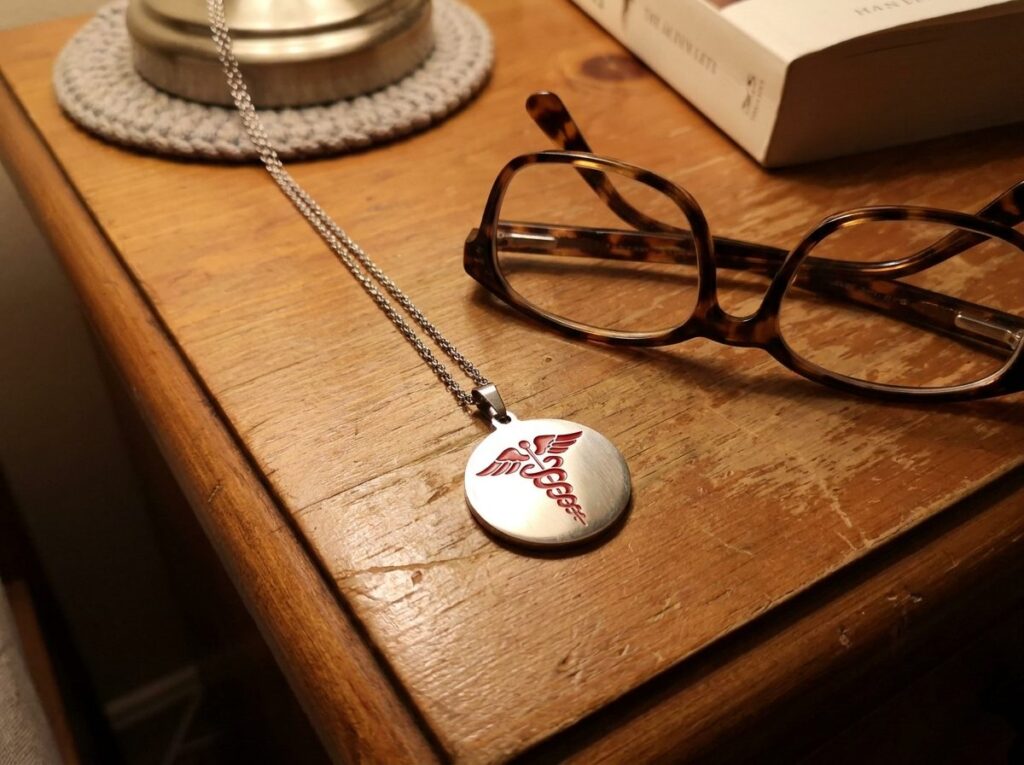 LifeFone medical alert pendant on a nightstand next to reading glasses